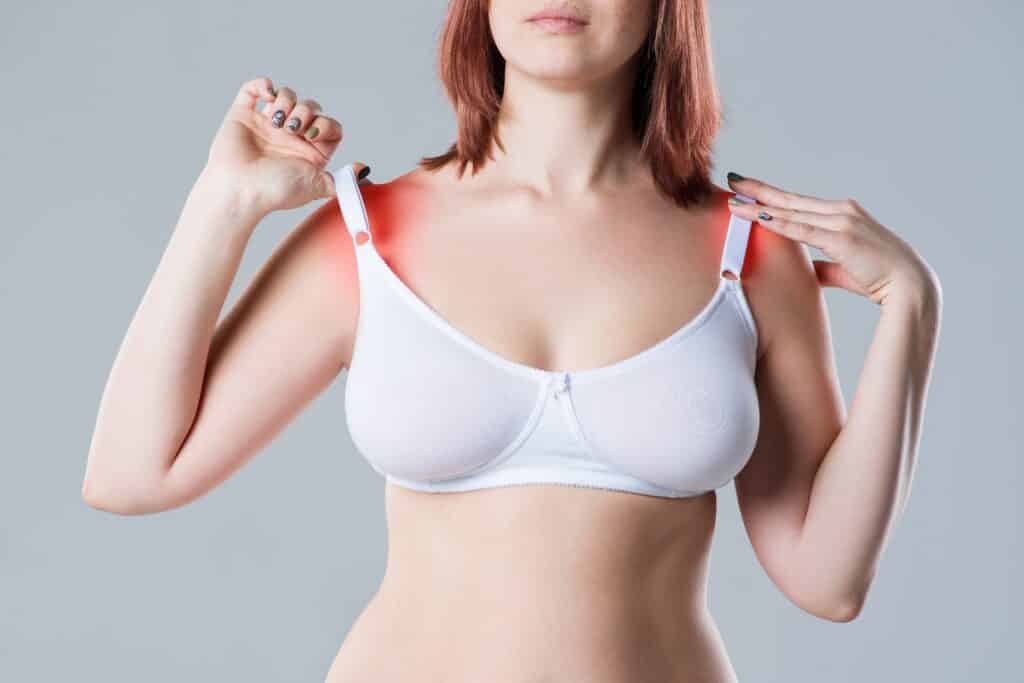 Woman with heavy breasts pulls her bras straps up before her breast reduction surgery